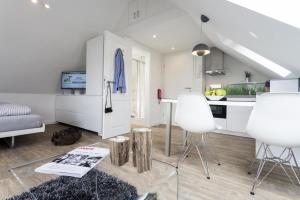 Haus Nordstern Wohnung 5 في بوركوم: مطبخ وغرفة معيشة مع دواليب بيضاء وكراسي بيضاء