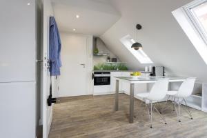 Haus Nordstern Wohnung 5 في بوركوم: مطبخ أبيض مع طاولة وكراسي بيضاء
