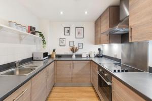 una cocina con electrodomésticos de acero inoxidable y armarios de madera en Tranquil Urban Haven, en Londres