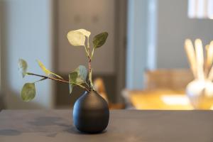 a black vase with a plant in it on a table at Sparkassengebäude Wohnung 5 in Borkum