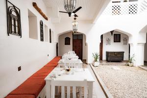 comedor con mesas blancas y chimenea en Zanzi House, en Zanzíbar