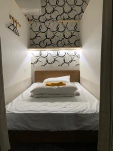 a bedroom with a bed with white sheets and a headboard at Shinjuku Sky hostel in Tokyo