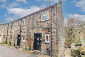 a large brick building with two doors on a street at Millpond Cottage in Holmfirth