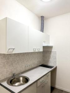 a kitchen with a sink and white cabinets at Votre Havre de Paix à Perpignan in Perpignan