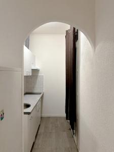 a kitchen with white cabinets and a hallway with an archway at Votre Havre de Paix à Perpignan in Perpignan