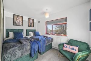 Ideal 4 bed House in Rugby - Football Table في Clifton upon Dunsmore: غرفة نوم بسريرين وكرسي أخضر