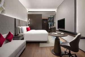a hotel room with a white bed and a tv at Ramada by Wyndham Qingdao Jiaodong International Airport in Qingdao