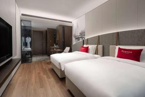 um quarto de hotel com duas camas e uma televisão em Ramada by Wyndham Qingdao Jiaodong International Airport em Qingdao