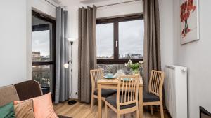 Apartamenty Sun & Snow City Link في وارسو: غرفة طعام مع طاولة وكراسي ونافذة
