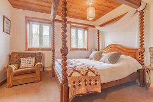 a bedroom with a four poster bed and a chair at Millrace Cottage in Holmfirth