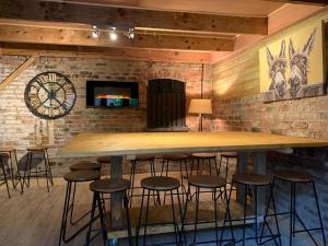 - un bar avec une grande table et des tabourets en bois dans l'établissement The Carriage House, Bilbrough York Sleeps 24, à Bilbrough