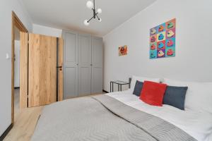 um quarto com uma grande cama branca e uma almofada vermelha em Fresh & Stylish Apartments in Poznań with Parking & Balcony by Renters em Poznań