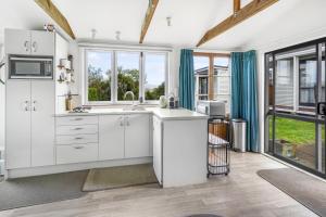a kitchen with white cabinets and a sink at The Shed - Raglan Holiday Home in Raglan