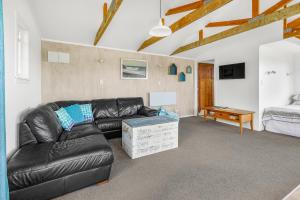 a living room with a leather couch and a bed at The Shed - Raglan Holiday Home in Raglan