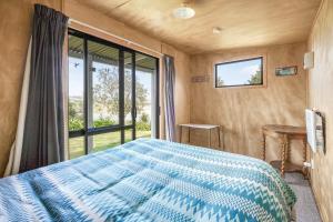 a bedroom with a bed and a large window at The Shed - Raglan Holiday Home in Raglan