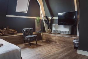 a room with a tv and a chair and a table at Tres Boutique Hotel in Gorinchem