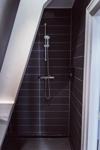baño con ducha de azulejos negros en Tres Boutique Hotel, en Gorinchem