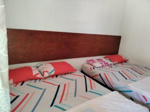 twee bedden met rode kussens in een kamer bij Niyaz Inn in Pantai Cenang
