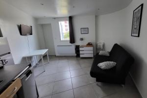 a living room with a black couch and a table at studio Les merles à Saint-Égrève in Saint-Égrève +5 photos