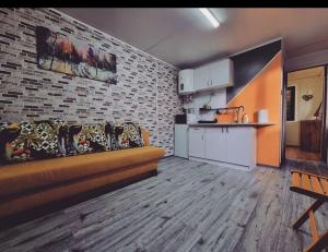a living room with a couch and a brick wall at Tiny House Căsuța cocoțată - Valea Doftanei - 2camere in Valea Doftanei