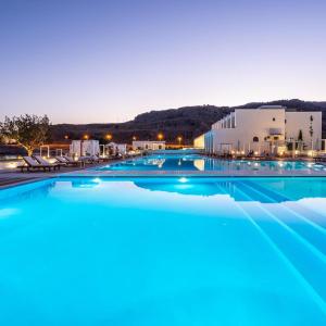 a large swimming pool with blue water at night at Kamari Beach in Lardos