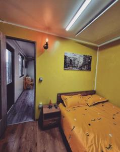 a bedroom with a bed with a yellow wall at Tiny House Căsuța cocoțată - Valea Doftanei - 2camere in Valea Doftanei