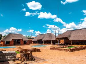 eine Gruppe von Gebäuden mit Strohdächern und blauem Himmel in der Unterkunft Bokamoso Lodge and Conference Centre 