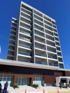 a tall building with people standing in front of it at Loft Marília City in Marília