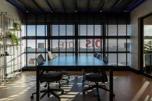a table and chairs in a room with large windows at Loft Marília City in Marília