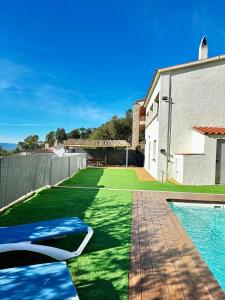 a backyard with green grass and a swimming pool at Casa MAJU in Pals