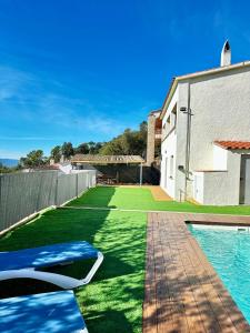 un patio trasero con césped verde y una piscina en Casa MAJU en Pals