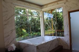 Chales Maria Flor في جونسالفيس: حوض استحمام في غرفة مع نافذة كبيرة