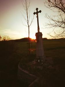 uma cruz num campo com o pôr-do-sol ao fundo em Statek u Sýkorky em Ostrov