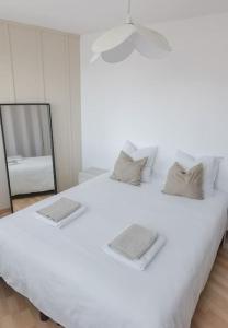a large white bed in a room with a mirror at Terre de Bretagne, appartement entre port et plage in Audierne