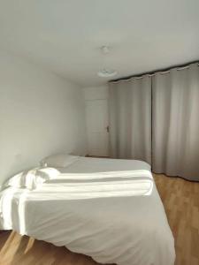 a white bed in a room with a curtain at Terre de Bretagne, appartement entre port et plage in Audierne