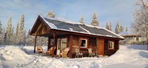 Cabaña de madera con sillas en la nieve en LAKESIDE AURORA CABINS en Kiruna