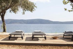 three picnic tables sitting next to a body of water at ILYA SUITES BY THE SEA in Alonnisos Old Town