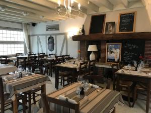 a restaurant with wooden tables and chairs and a chalkboard at Logis Hôtel & Restaurant "Au Gré du Vent" in Berck-sur-Mer