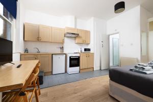 倫敦的住宿－Large Studio on Finchley Road 10，一个带木制橱柜的厨房和一张位于客房内的床