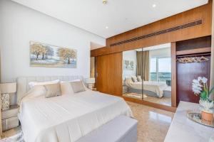 1 dormitorio con 1 cama blanca y sala de estar en Private Beach - 4BR - 8 Sleep - Pool - 180 grades Sea & Ain View - Huge Balcony - Parking - Prime Location, en Dubái