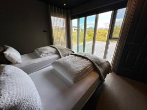 two beds sitting in a room with a window at Stunning Luxury Chalet in West Iceland in Reykholt