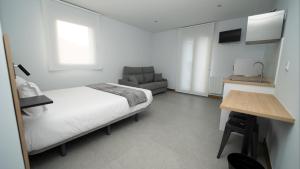 a bedroom with a bed and a chair and a table at Apartamentos Puerta de Occidente in Cornellana