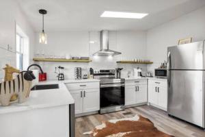 Una cocina con gabinetes blancos y un refrigerador de acero inoxidable. en Starlight Horizon 2 Cabins CD - Side-by-Side Group Retreat - Pet-Friendly Texas Hill Country Cabins Near Canyon Lake - Pool, Stargazing, Sleeps 16, en Canyon Lake