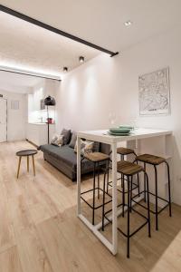 sala de estar con mesa blanca y taburetes en Charming Malasaña Vibes - Alquileres Temporales, en Madrid