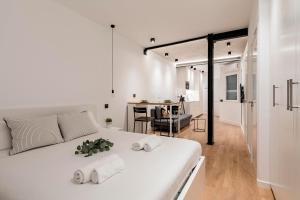 1 dormitorio blanco con 1 cama blanca grande y 2 toallas en Charming Malasaña Vibes - Alquileres Temporales, en Madrid