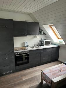 a kitchen with black cabinets and a sink and a window at Haus-Sonneck in Esens