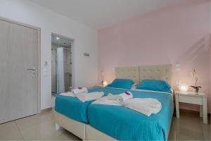 een slaapkamer met een blauw bed en handdoeken bij Palotel Design Gouvia in Gouvia