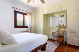 a bedroom with a bed and a chair and a window at Authentic 4BR Pool & Sauna Villa, Sant Agusti in San Antonio Bay