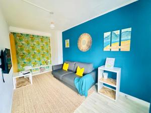 - un salon avec un canapé et un mur bleu dans l'établissement Ipanema, au Centre ville de Lens, à Lens