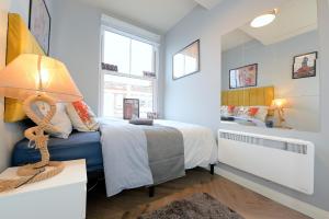 a bedroom with a bed and a table with a lamp at 2 BED TERRACED FLAT PICCADILLY LINE in London